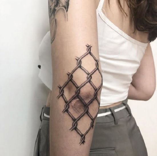 Codo tatuado con una cerca