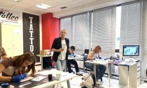 Instructora de tatuaje experta guiando a las alumnas durante la primera sesión práctica en piel sintética en Tattoo School Madrid