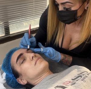 alumna del curso de micloblading y micropigmentación realizando un servicio a una voluntaria durante el curso impartido en Tattoo School Madrid