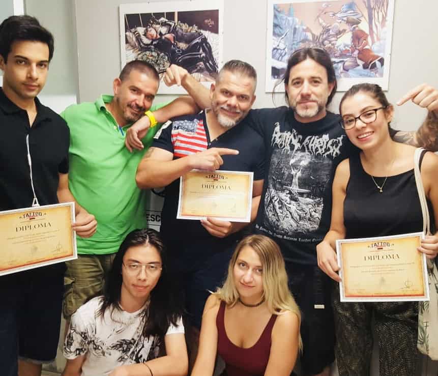 Grupo de estudiantes y profesores en la Escuela de Tatuajes Madrid, celebrando diplomas.
